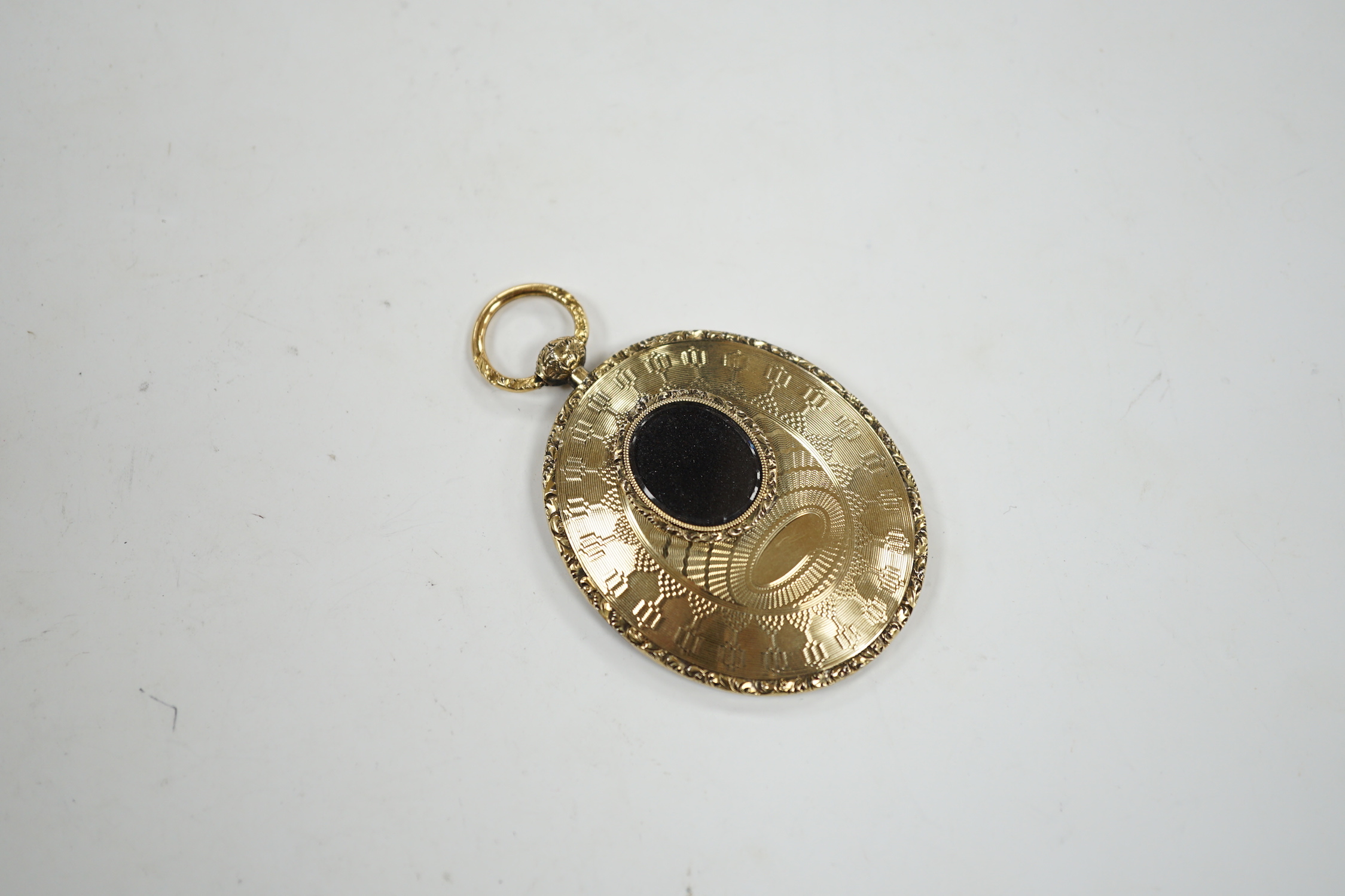 An engine turned yellow metal oval mourning locket, verso with small glazed oval panel, 56mm.
